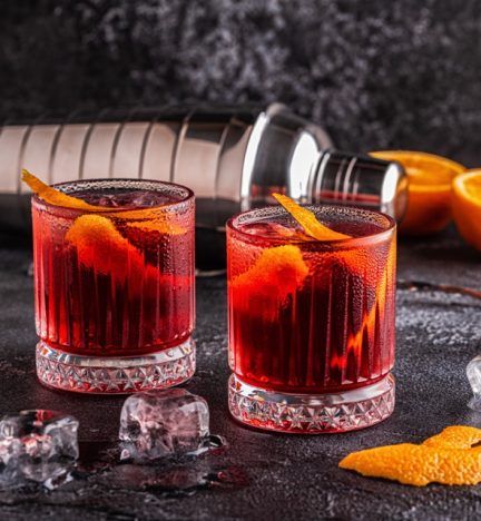 Negroni cocktail with orange peel and ice, selective focus.